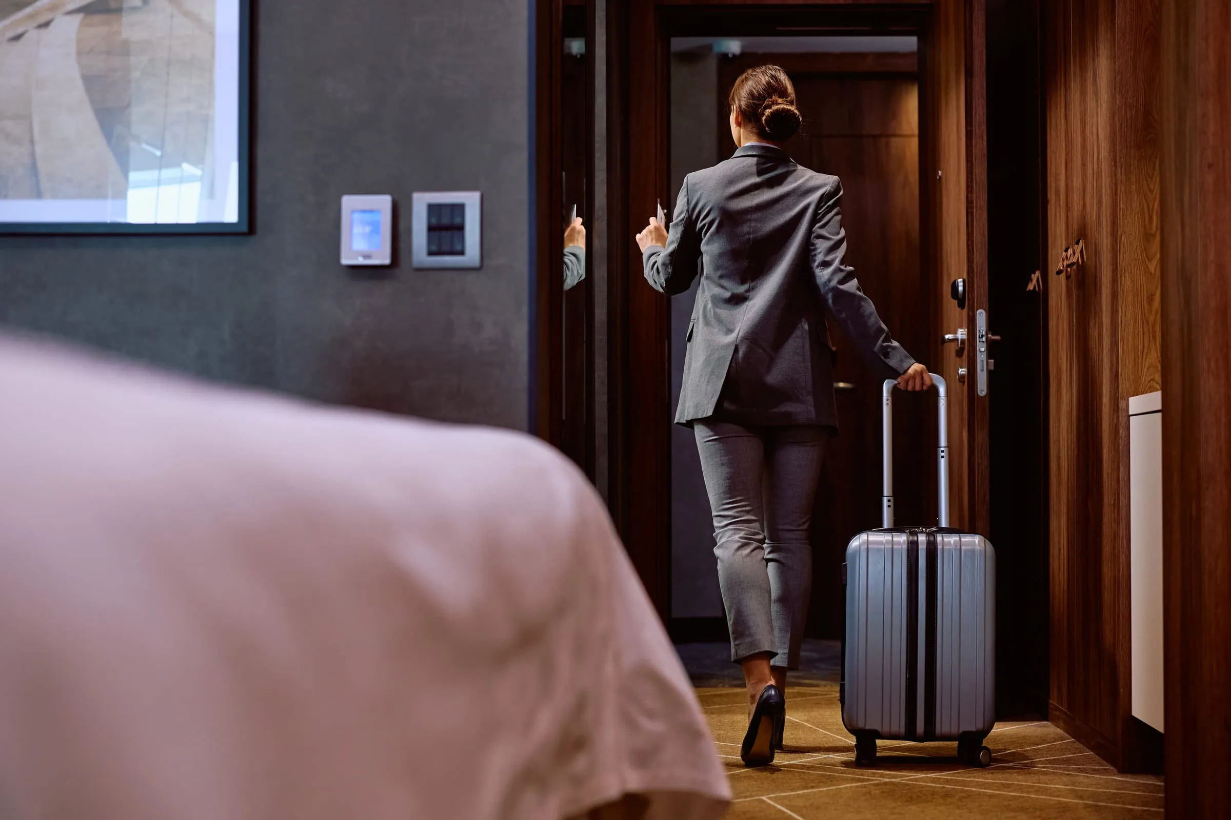 Guest arriving at a hotel with luggage beside a wall control panel