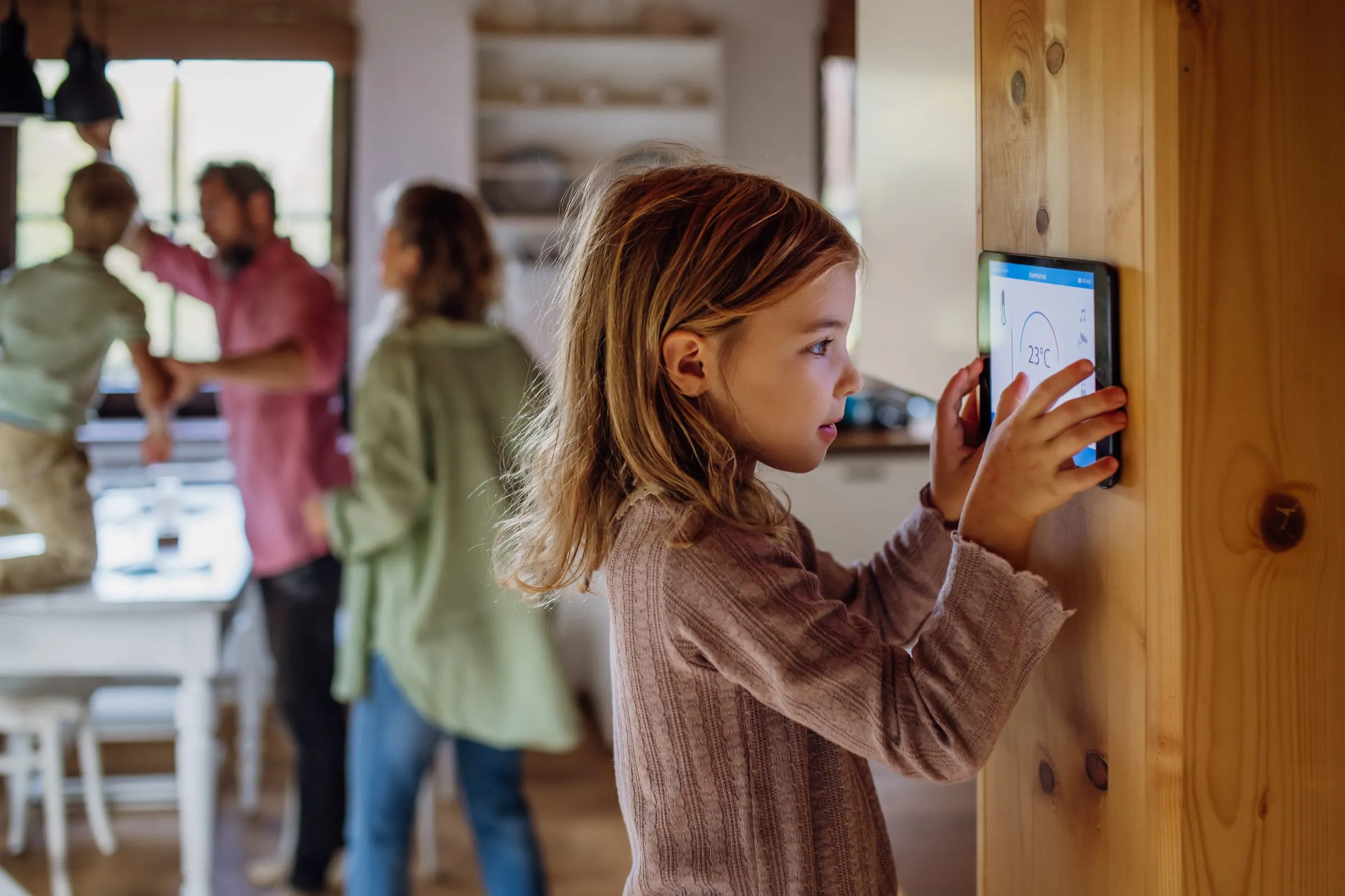 Family adjusting a wall tablet in a living room